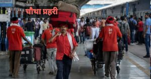 रेलवे स्टेशन पर यात्रियों का सामान ले जाते कुली